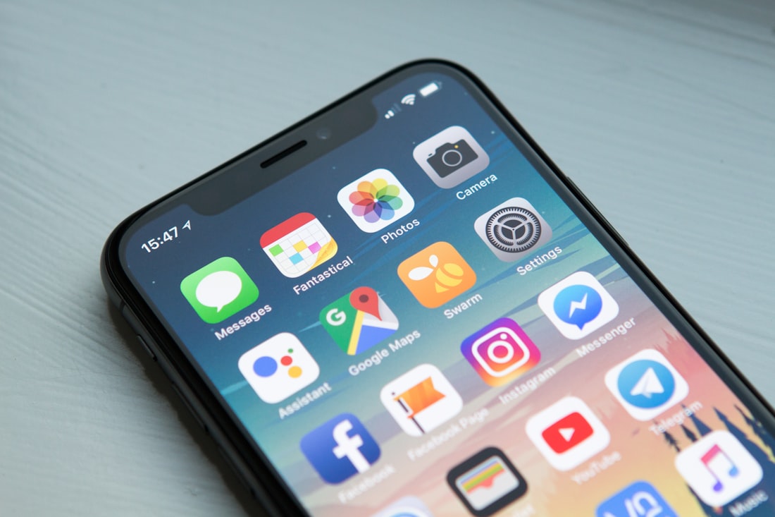 Persoon kijkt 's avonds naar een smartphone in het donker — blauw licht onderdrukt melatonine en vertraagt het inslapen