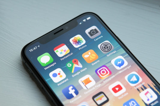 Persoon kijkt 's avonds naar een smartphone in het donker — blauw licht onderdrukt melatonine en vertraagt het inslapen