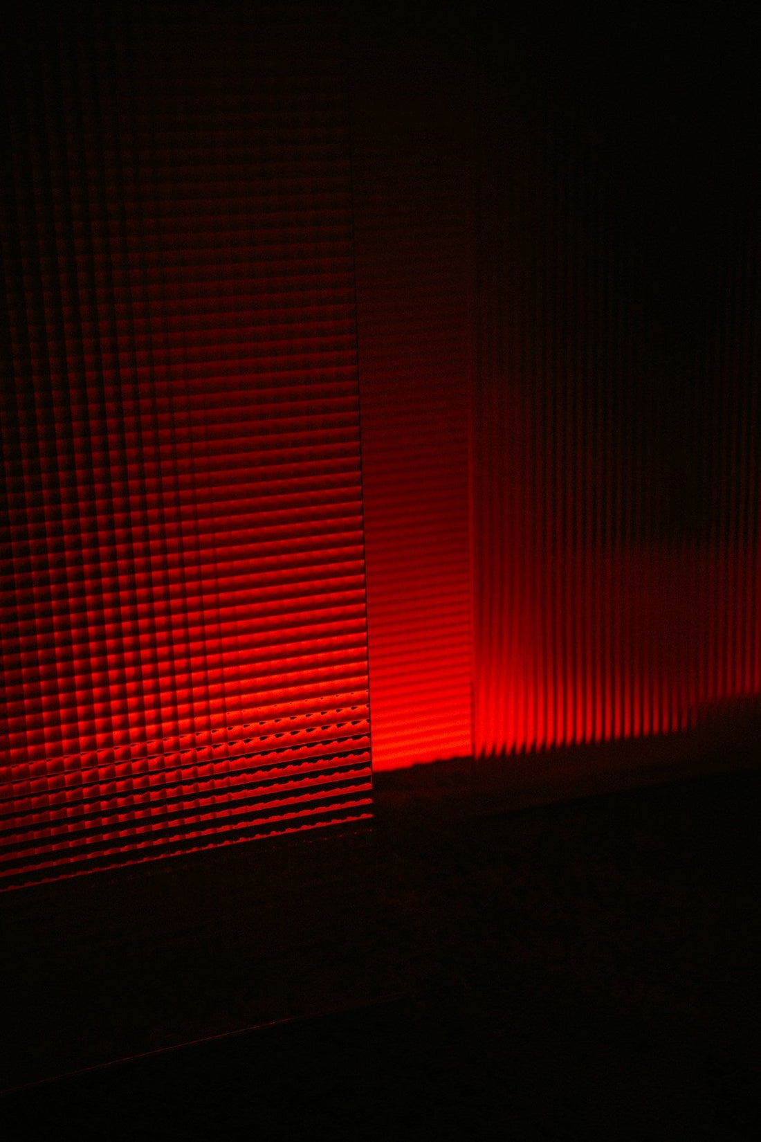 Persoon ontspant onder een professioneel rood lichtpaneel — roodlichttherapie voor betere slaap, herstel en melatoninebalans