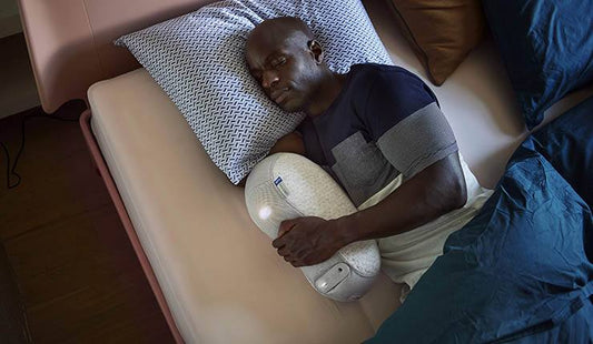 Man slaapt met Somnox slaaprobot — innovatieve slaaptechnologie die ademhaling simuleert voor diepere ontspanning en betere slaap