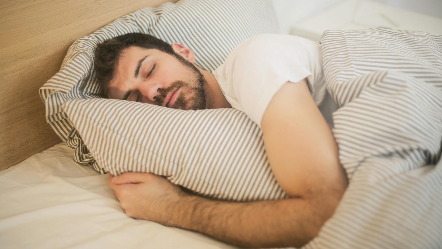 Slapende jonge man in een bed